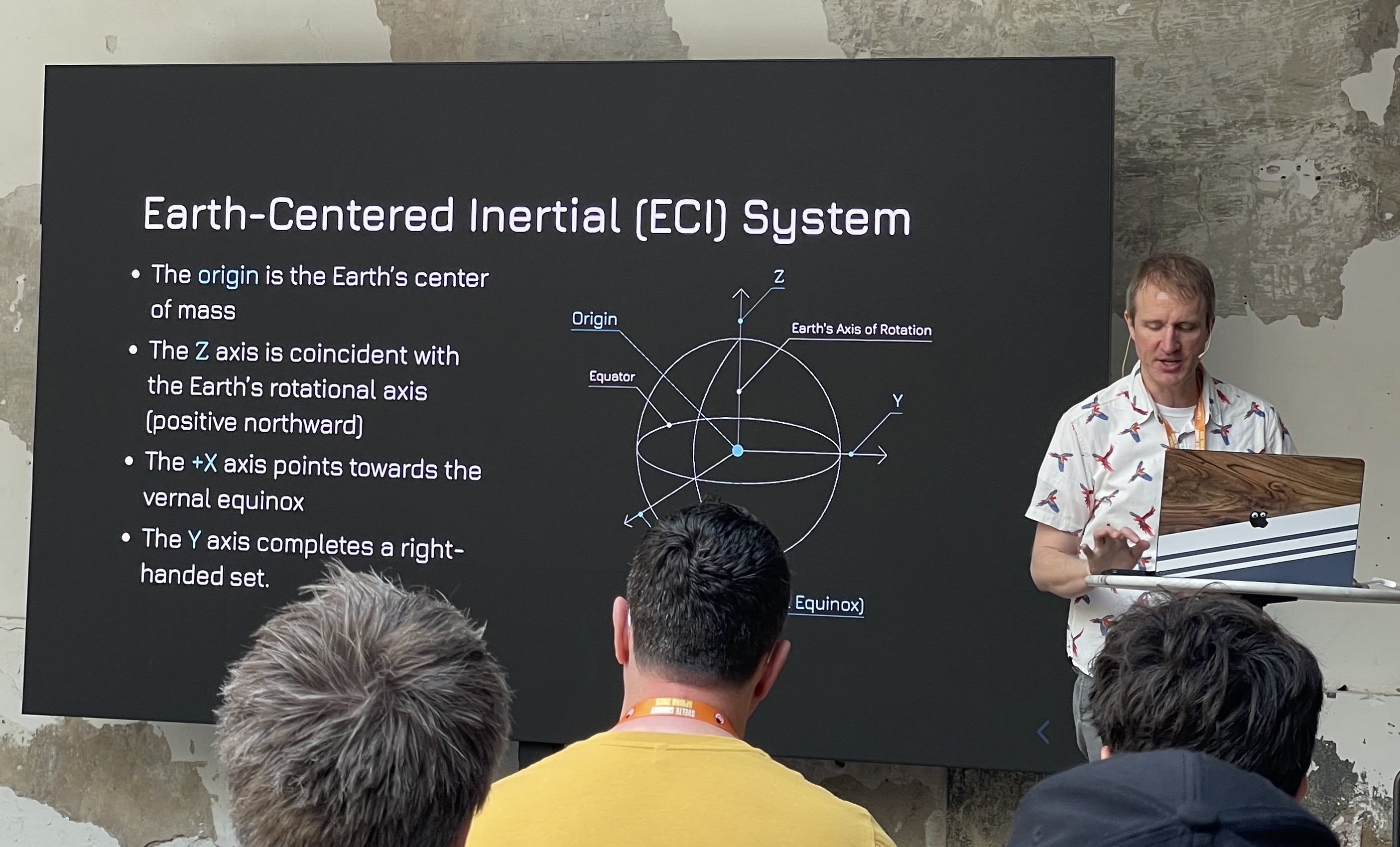 A photo during Mike Rourke's talk. A slide explains the Earth-Centered Inertial System.