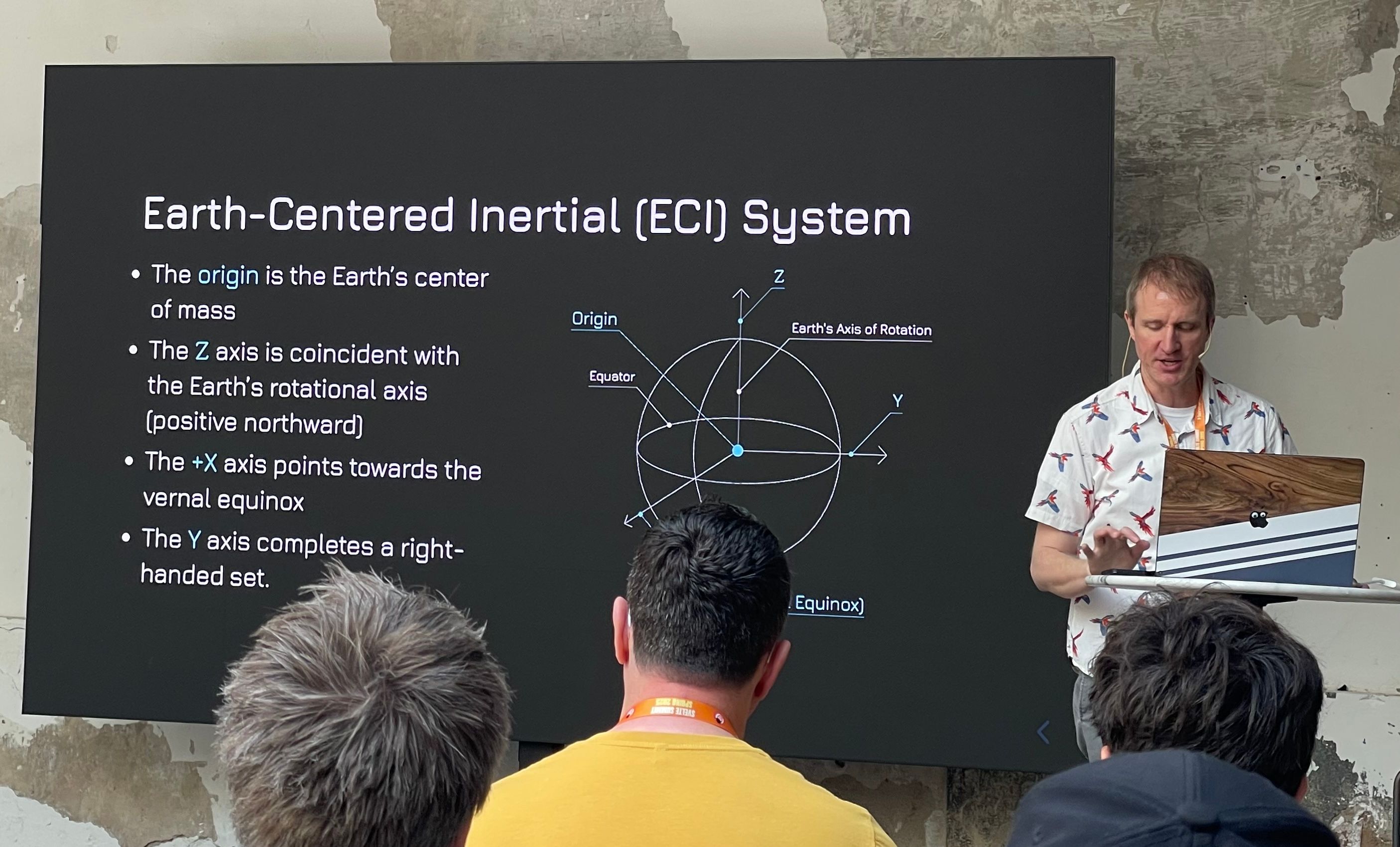 A photo during Mike Rourke's talk. A slide explains the Earth-Centered Inertial System.